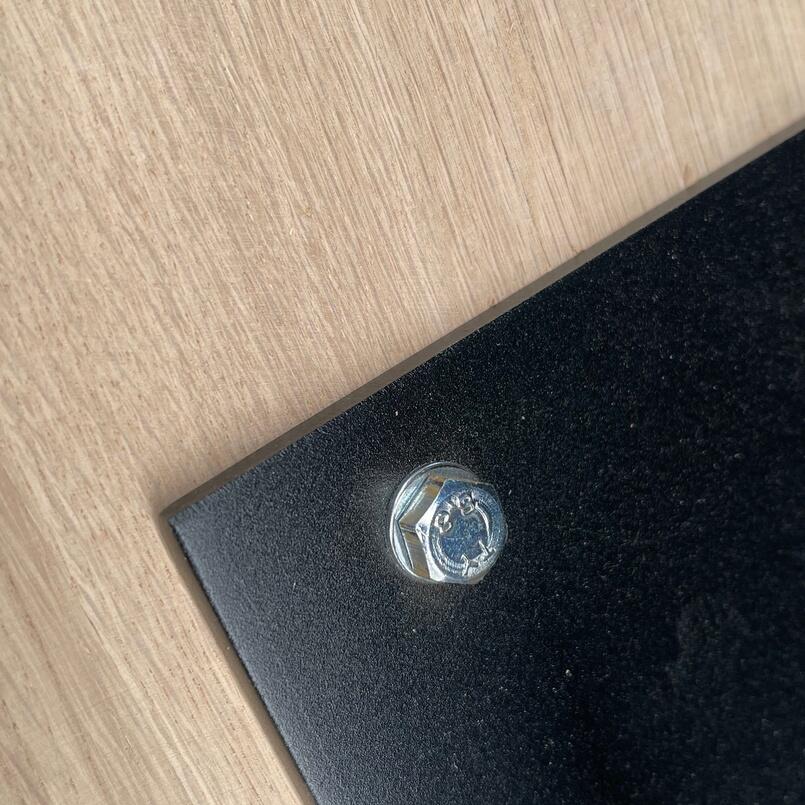 Detailaufnahme einer Tischplatte aus geschliffenem Eichenholz mit Metallgewinden im Holz