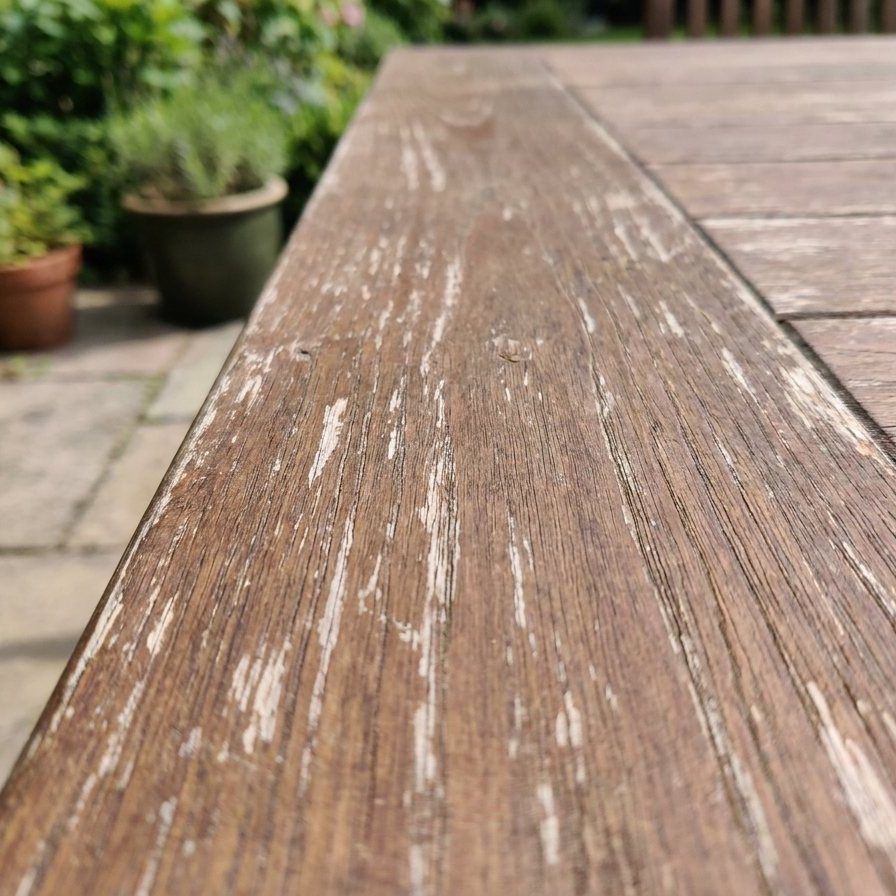 Nahaufnahme einer fein gemaserten Kante aus edlem Sucupira Holz auf einer Gartenterrasse