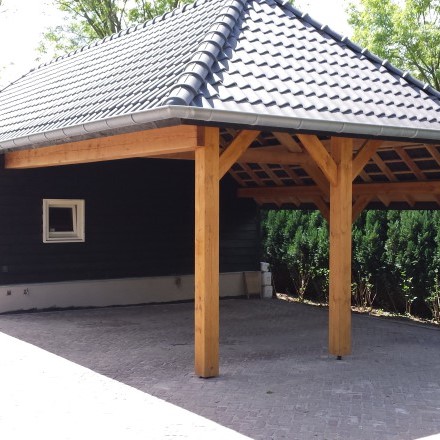 Ein eleganter Carport aus Douglasienholz mit Ziegeldach schützt Fahrzeuge stilvoll vor der Witterung