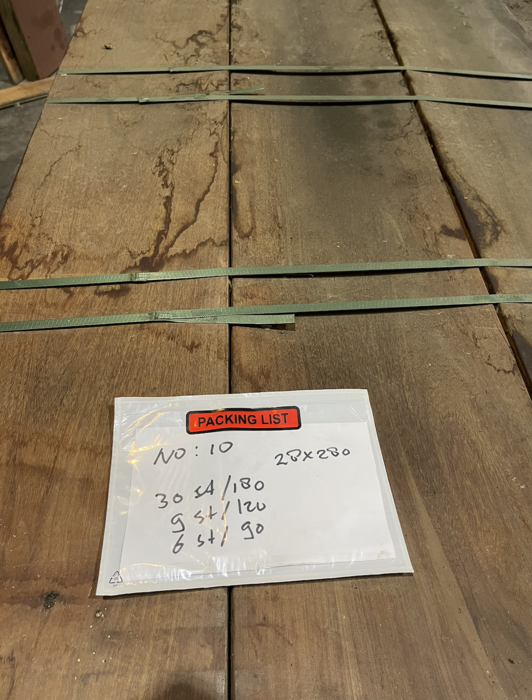 Massive breite Hartholzbretter lagern auf einer Palette bereit für den Bau im Garten