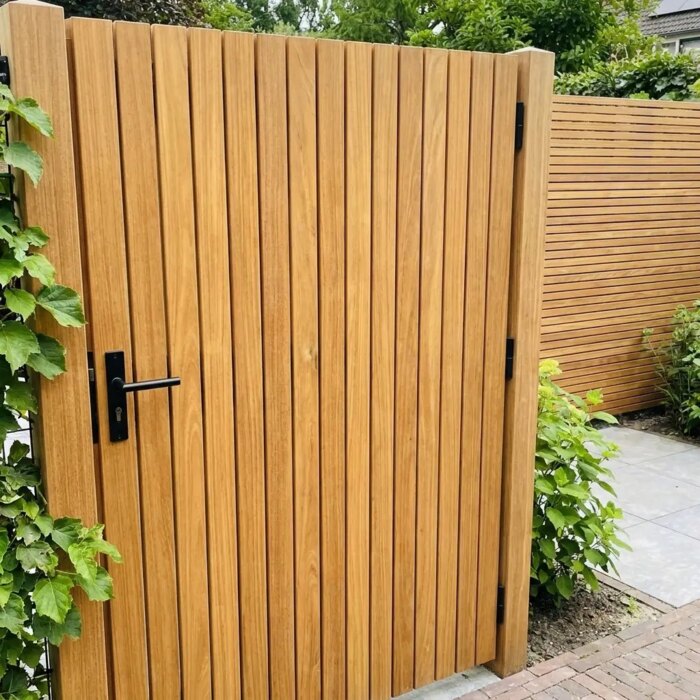 Gartentor aus Teakholz mit 5 cm Lamellen neben einer Kletterhortensie, mit schwarzem Türdrücker