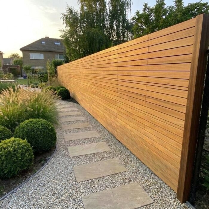 Langer Teak Zaun mit 5 cm Lamellen entlang eines Gartenwegs, sauber in der Flucht
