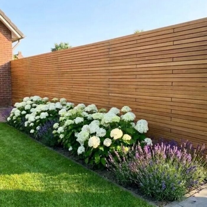 Hinter einem Beet: Sichtschutzzaun aus Teak mit 5 cm Lamellen hinter weißen Hortensien und Lavendel