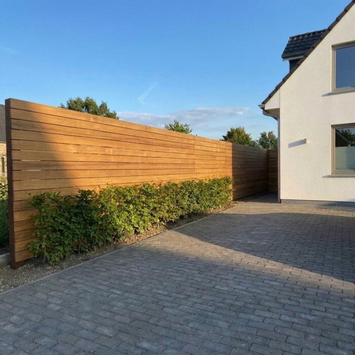 Entlang der Einfahrt: Teak Zaun mit 9 cm Lamellen entlang einer Einfahrt mit Buchenhecke