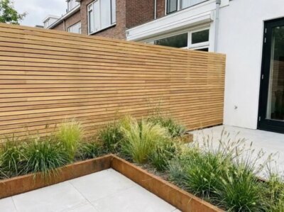 Teak Zaun mit 5 cm Lamellen im Reihenhausgarten mit Pflanzbeet aus Cortenstahl