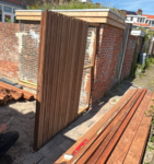 Moderner Ipé Barcode Zaun mit vertikalen Holzlamellen vor exklusiver Architektur