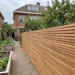 Ipe Zaun mit 5 cm Lamellen neben einem Gemüsegarten mit Hochbeeten