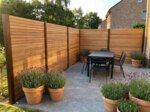 Teak Sichtschutz mit 7 cm Lamellen über Eck an einer Terrasse mit Esstisch