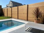 Teak Sichtschutzzaun mit 9 cm Lamellen an einem Pool im modernen Garten