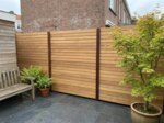 Teak Zaun mit 9 cm Lamellen in einem Stadtgarten mit Fächerahorn