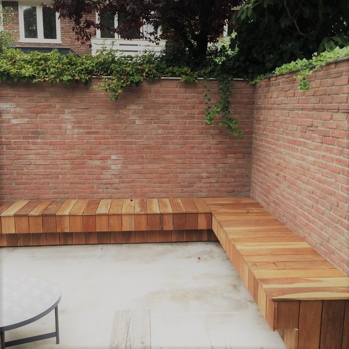 Luxuriöse Ipé-Hartholz-Eckbank montiert an einer Gartenmauer aus Stein