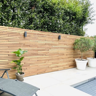 Horizontaler Ip&eacute;-Lamellenzaun mit Wandstrahlern und Pflanzk&uuml;beln auf einer Terrasse
